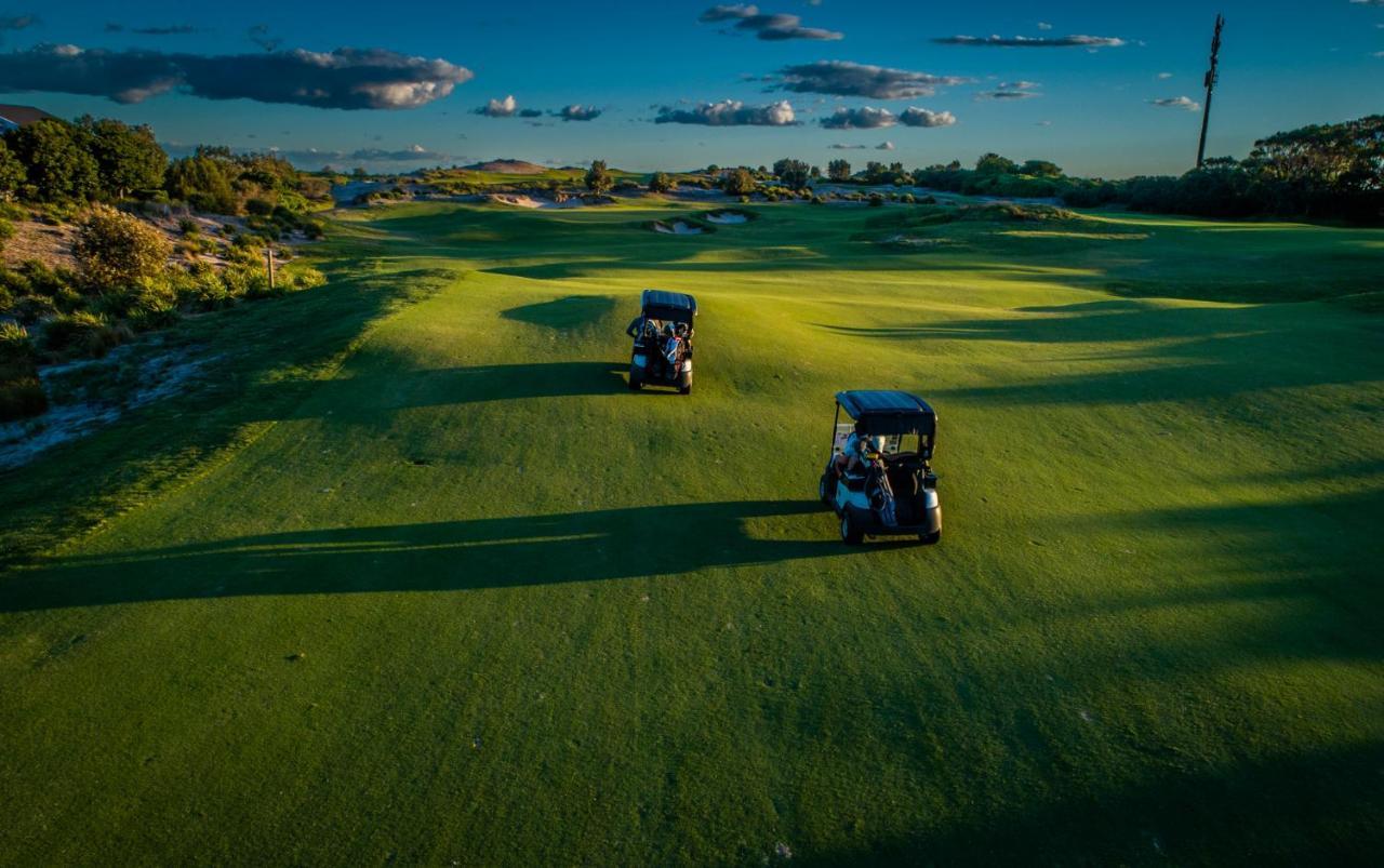 Pullman Magenta Shores Resort Entrance Exteriér fotografie Golf carts on the green